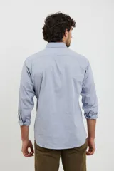 Camisa celeste de algodón con cuello abotonado, manga larga con puños abotonados y bolsillo en el pecho. Corte clásico.