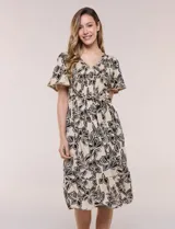 Vestido midi de rayón en color beige con estampado floral en negro, escote en V, pechera con punto smock, mangas cortas acampanadas con detalle de galón y falda evasé con volado en el ruedo. Incluye lazo textil ajustable en la cintura.