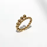 Anillo dorado de acero con diseño de borlas macizas de tamaño decreciente que se cruzan en el frente.