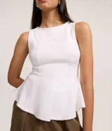 Blusa sin mangas de color blanco confeccionada en tejido punto roma. Presenta un diseño peplum alargado con breteles anchos y volados en el ruedo. Marca Blue Steel.