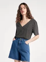 Blusa de cuello en V con estampado geométrico de líneas blancas sobre fondo azul marino.