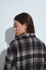 Campera de paño con diseño de cuadros en tonos negro, gris y beige. Presenta cuello camisero, cierre frontal con botones y corte corto.