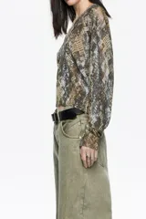 Jersey de corte recto con escote en V y mangas largas, confeccionado en viscosa con fibras metalizadas que aportan un sutil brillo con estampado de piel de serpiente.