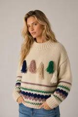 Sweater de lana merino color beige, con diseño tejido de punto jacquard estilo nórdico en tonos marrón, negro, blanco y lila en el pecho y las mangas. Cuenta con cuello redondo, puños y dobladillo acanalados.