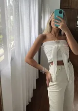 Top negro con diseño cruzado en el frente, estilo halter y con detalles de tachas doradas.