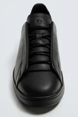 Zapatilla de estilo minimalista confeccionada en piel, con diseño de cordones ocultos, horma redonda y suela a tono.