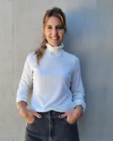 Polera de manga larga en tejido acanalado color blanco, con cuello alto y puños con detalle de punto smock fruncido.