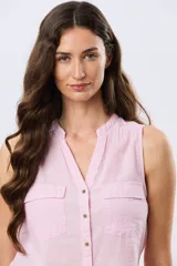 Musculosa de lino color rosado, sin mangas, con cuello en V, cierre frontal con botones y bolsillos plaqué con solapa en el pecho.