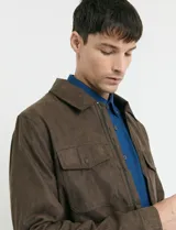 Campera Harrington de gamuza en color marrón, con cierre frontal, cuello clásico y bolsillos laterales con solapa.