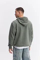 Canguro oversize de algodón con capucha y cordones ajustables. Presenta un diseño de estampa frontal con la frase 'GREAT TIMES' en relieve y bolsillo frontal tipo canguro.