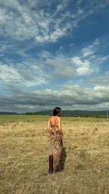 Vestido largo de fiesta con estampado animal print en tonos marrones. Presenta un diseño con breteles trenzados que se cruzan y envuelven el cuerpo, con una caída fluida y elegante.