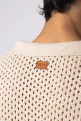 Camisa de manga corta tejida en algodón con diseño calado, cuello tipo bowling y cierre frontal con botones al tono.