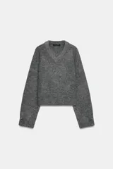Jersey de punto suave con cuello en V y manga larga, con detalle de botones metálicos en los puños.