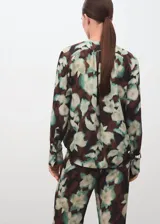 Blusa de gasa con estampado floral en tonos marrón, verde y crudo, escote en V con lazo ajustable y mangas largas con puños abotonados.
