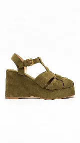 Sandalias de plataforma con taco corrido y tiras cruzadas en la parte delantera, confeccionadas en gamuza de color verde militar. Cuentan con pulsera al tobillo ajustable con hebilla metálica dorada.