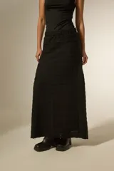 Pollera larga de corte recto y cintura elástica, confeccionada en tejido negro con textura de franjas horizontales.