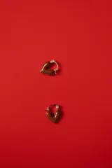 Aros tipo argolla con dije en forma de corazón esmaltado en color marrón chocolate y detalles metálicos dorados.