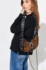 Cartera tipo baguette negra de cuero vacuno con textura tipo piel de cocodrilo. Tiene correa de cuero ajustable con detalles de tachas y cadena metálica plateada. El frente presenta un aplique de cuero con hebilla metálica plateada con tachas.