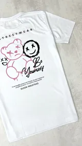 Remera blanca de manga corta con estampado en la espalda que incluye un oso de peluche, una cara sonriente y la frase "Be Yourself".