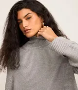 Suéter alargado de punto color rojo, con cuello alto ajustado y mangas largas ajustadas.