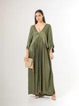 Vestido largo de satén italiano color verde militar, con escote en V profundo, corte oversized de caída amplia y fluida, y mangas tres cuartos con detalles de volados en los puños.