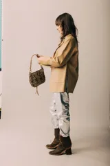 Blazer de cuero color celeste metalizado, con solapas, cierre con broches tipo tanca de madera y puños con detalle de piel sintética marrón.