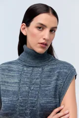 Chaleco de punto azul con cuello alto y diseño de trenzas.