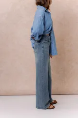 Pantalón de jean con tiro alto y corte wide leg, de color azul con efecto desgastado. Cuenta con cierre y botón frontal, además de bolsillos funcionales.