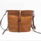 Cartera de gamuza color marrón con diseño estructurado, correa ajustable y detalle de tira central con hebilla metálica. Presenta apliques de tachas metálicas en las esquinas inferiores y correa larga extraíble.