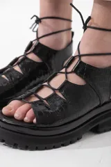 Sandalias de cuero color marrón con textura de cocodrilo, plataforma con suela track y tiras finas que se atan al tobillo.