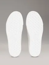 Zapatillas de plataforma Calvin Klein con diseño de jacquard monograma en tonos beige, suela blanca gruesa y cordones blancos.