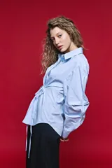 Camisa blanca de manga larga con volumen y estructura, cierre frontal con botones y lazo ajustable en la cintura que realza la silueta.