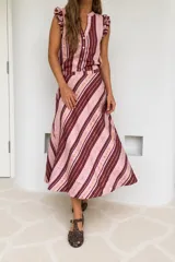 Pollera midi evasé confeccionada en mezcla de lino con diseño a rayas diagonales en tonos rosado y bordó con detalles metalizados. Presenta corte en la cintura y movimiento fluido.