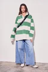 Sweater estilo polo de corte oversize, con diseño de rayas horizontales anchas en tonos camel y bordó. Presenta cuello camisero con cierre frontal parcial y mangas largas con puños ajustados.