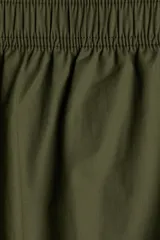 Pantalón de algodón color verde militar, de corte ancho y tobillero. Presenta cintura elástica fruncida y piernas amplias.