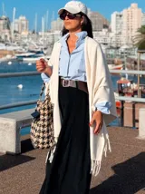 Ruana color crema con flecos en los bordes, de diseño abierto y holgado.