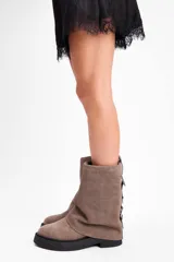 Bota de caña media confeccionada en cuero vacuno color marrón oscuro, con diseño de pliegues en la caña y suela de goma al tono con textura estriada.