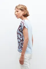 Blusa celeste con estampado floral en tonos marrones, de corte clásico, cuello en V y mangas cortas.