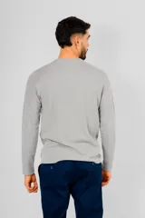 Buzo de manga larga con cuello redondo, confeccionado en tejido de punto con textura tipo waffle. Presenta un diseño minimalista con una pequeña etiqueta decorativa en el ruedo inferior.