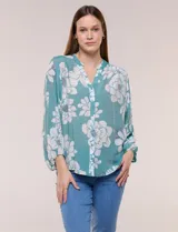 Blusa holgada de gasa texturizada color blanco con estampado de lunares negros, escote en V con botones frontales, mangas 3/4 abullonadas y puños elásticos.