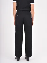 Pantalon de corte recto y tiro medio, confeccionado en tela de algodón color negro, con cierre frontal y bolsillos laterales.
