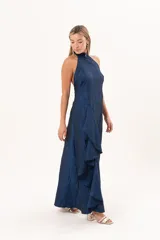 Vestido largo azul de tafeta con textura corrugada, cuello halter, espalda descubierta y falda amplia con tajo lateral y volados.