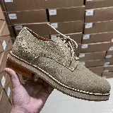 Zapato acordonado de gamuza color beige, con suela de goma y detalle de perforaciones en el talón.