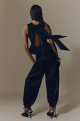 Pantalón tobillero negro de tejido arrugado, con cintura de tiro alto, pliegues delanteros y corte holgado de piernas barrel con elástico y cordón ajustable en los tobillos.