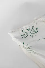 Pareo de playa blanco con estampado de hojas verdes y borde de encaje con flecos.