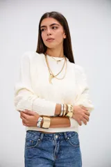 Sweater de punto con diseño de trenzas, color crudo, de cuello redondo y manga larga con puños acanalados.