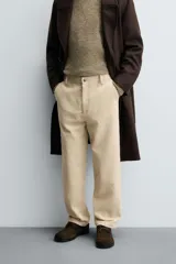 Pantalón de corte regular fit confeccionado en pana de algodón color beige, con bolsillos frontales, bolsillos traseros de plastrón y cierre frontal con cremallera y botón.