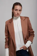 Saco blazer color beige con solapas de muesca, cierre frontal con dos botones, bolsillos laterales con solapa y corte recto.