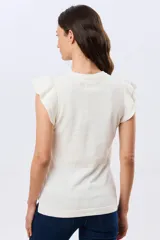 Remera tejida de algodón en color beige, de cuello redondo, sin mangas y con detalles de volados estructurados en los hombros.