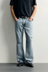 Jeans flare fit de denim negro, tiro medio, ajustados arriba y con botamanga acampanada. Cuentan con cinco bolsillos, lavado efecto gastado y bajo con acabado irregular. Cierre frontal con cremallera y botón.